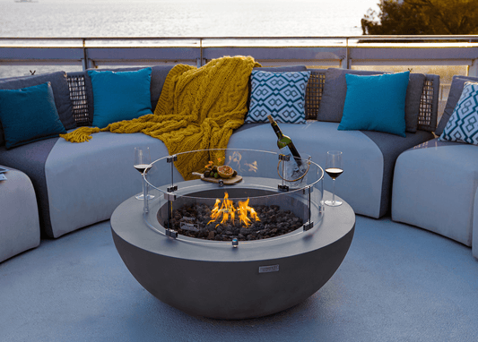 Table Brasero Lunar Bowl gris clair au design cylindrique qui réchauffe sur une terrasse