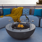Table Brasero Lunar Bowl gris clair au design cylindrique qui réchauffe sur une terrasse